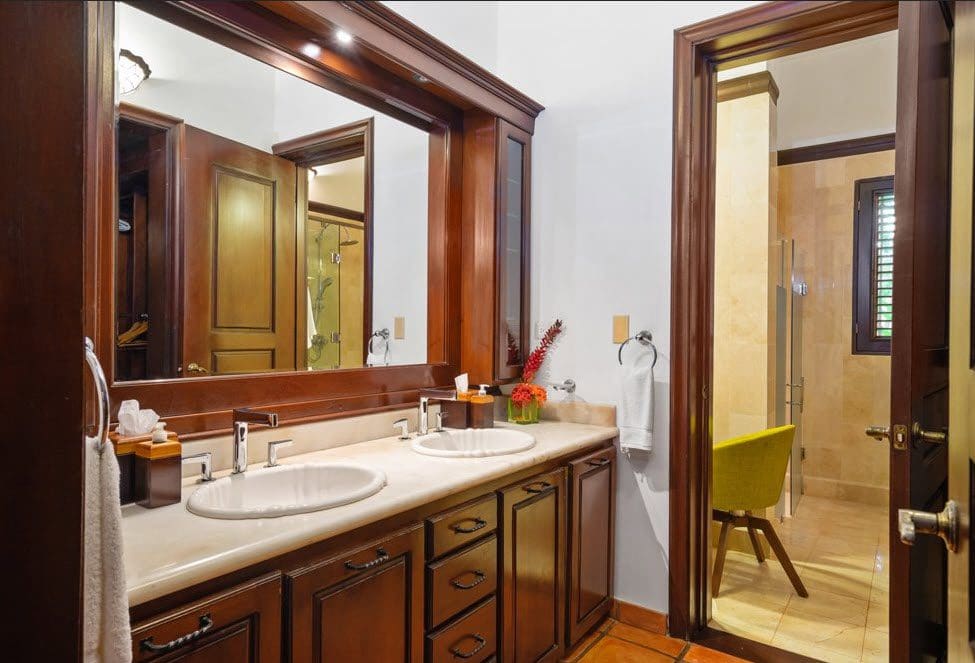 buyDRproperty Luxury bathroom with wood cabinets and double sinks in a stunning oceanfront villa. Sosua Real Estate