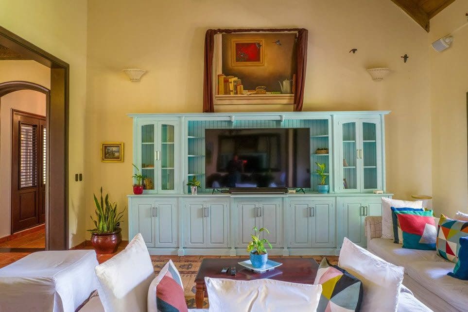 buyDRproperty Living room in a stunning oceanfront villa in the Dominican Republic. Light blue entertainment center, sofa, and plants. Sosua Real Estate
