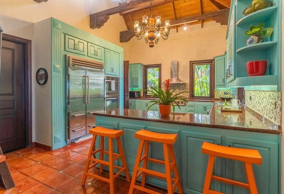 buyDRproperty Stunning kitchen in a luxury oceanfront villa with turquoise cabinets and orange bar stools. Sosua Real Estate