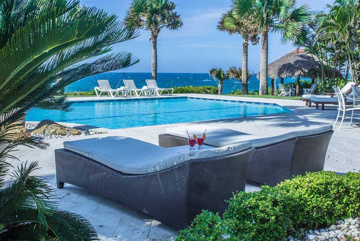 buyDRproperty Chaise lounges by a pool at a stunning oceanfront villa with ocean views in the Dominican Republic. Sosua Real Estate