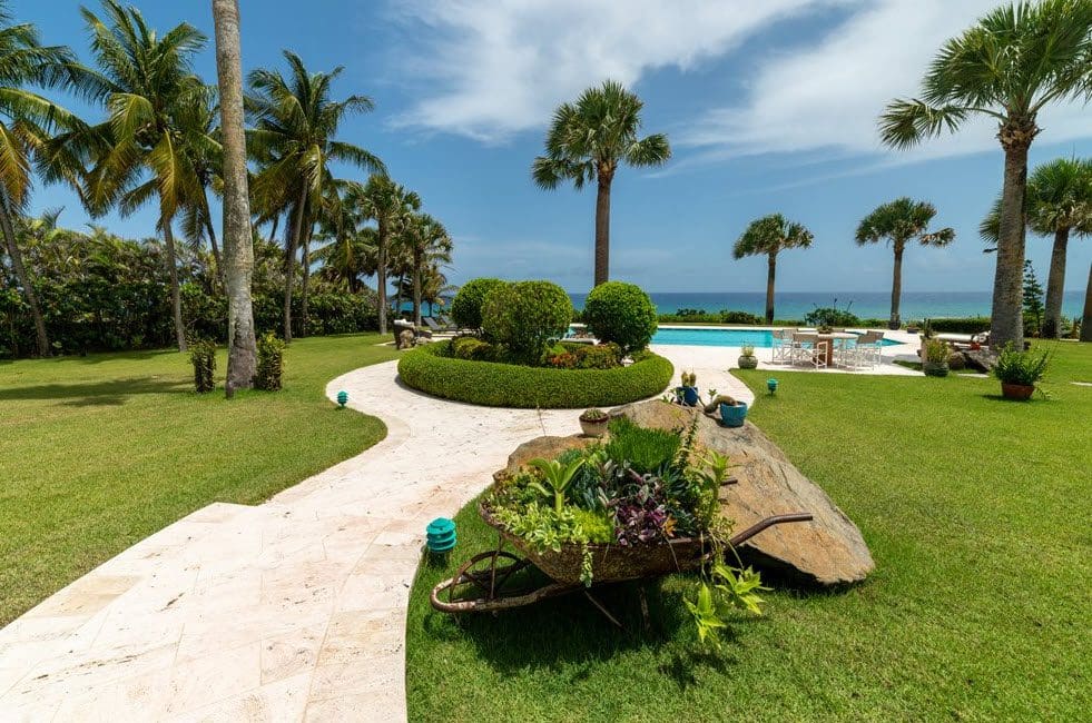 buyDRproperty Stunning oceanfront villa with lush landscaping and a pathway leading to the pool Sosua Real Estate