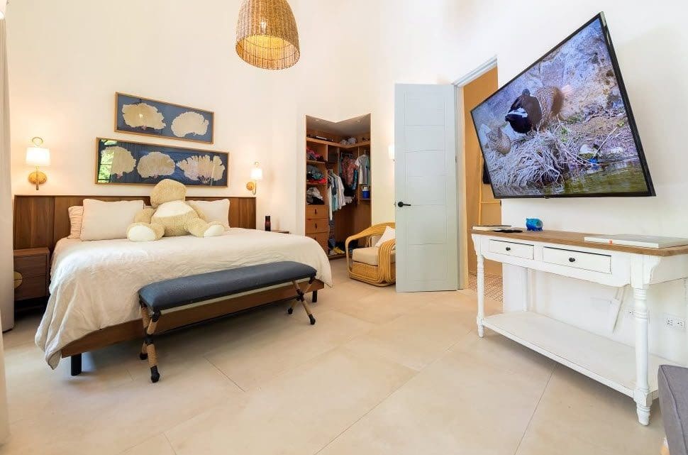 buyDRproperty Bedroom in the Stunning Villa SUNSET For Sale, featuring a large TV, bed, and walk-in closet. Sosua Real Estate