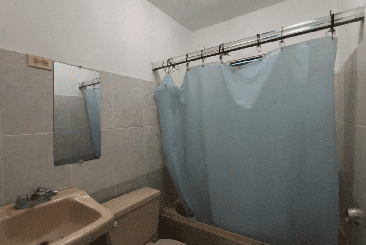 buyDRproperty Bathroom with a shower curtain, sink, and mirror in a hostel business. Sosua Real Estate