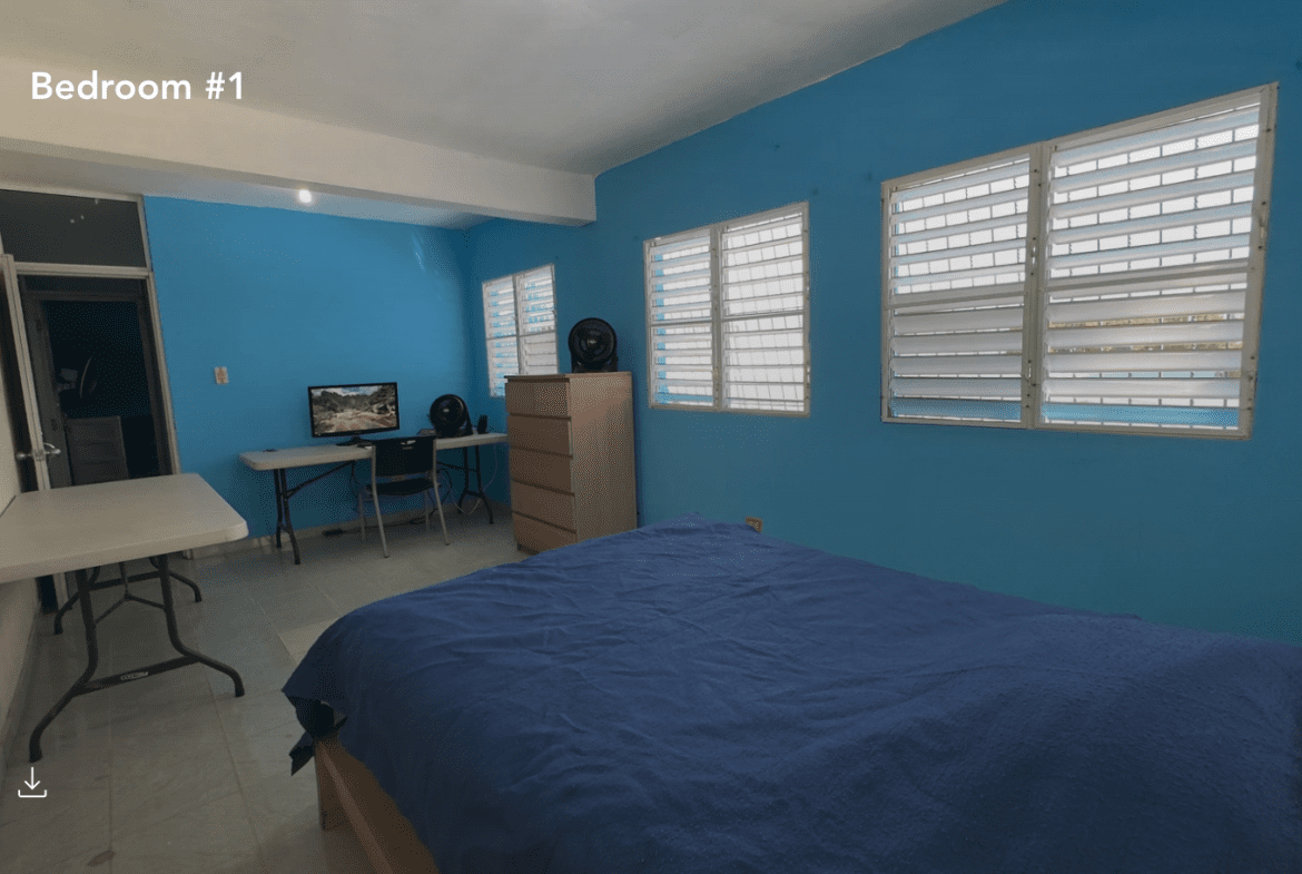 buyDRproperty Bedroom in a hostel business with a bed, desk, and windows. Sosua Real Estate