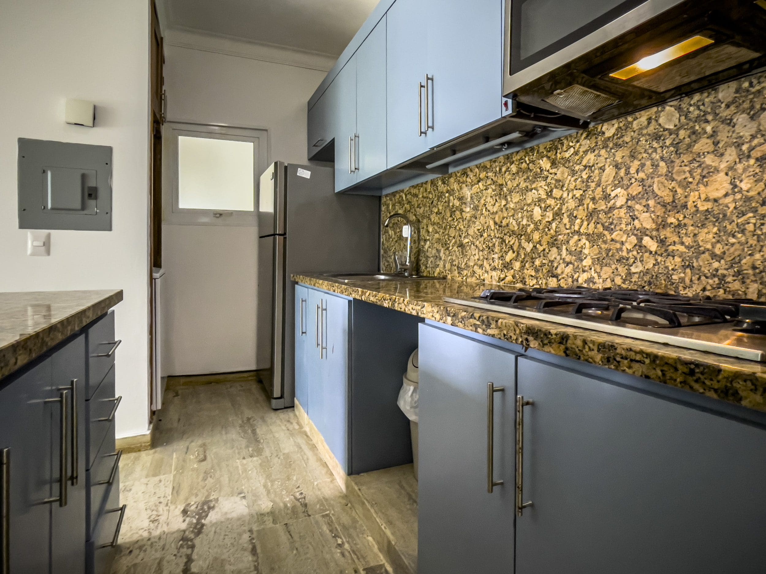 buyDRproperty Kitchen in a 3 Bedroom Oceanfront Condo with blue cabinets, granite countertop, and gas stove. Sosua Real Estate