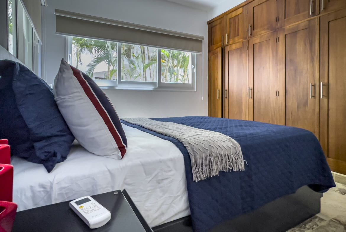 buyDRproperty Bedroom in a 3 Bedroom Oceanfront Condo with blue comforter and wooden closet. Sosua Real Estate