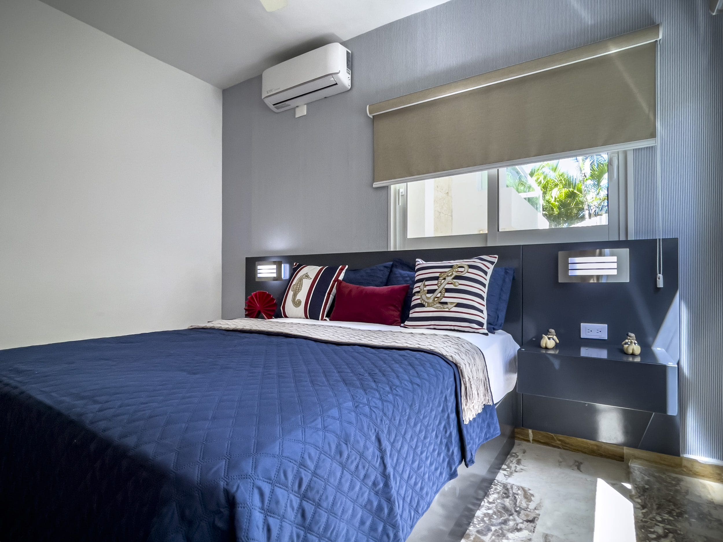 buyDRproperty Blue bed in a 3-bedroom oceanfront condo bedroom with nautical-themed pillows. Sosua Real Estate