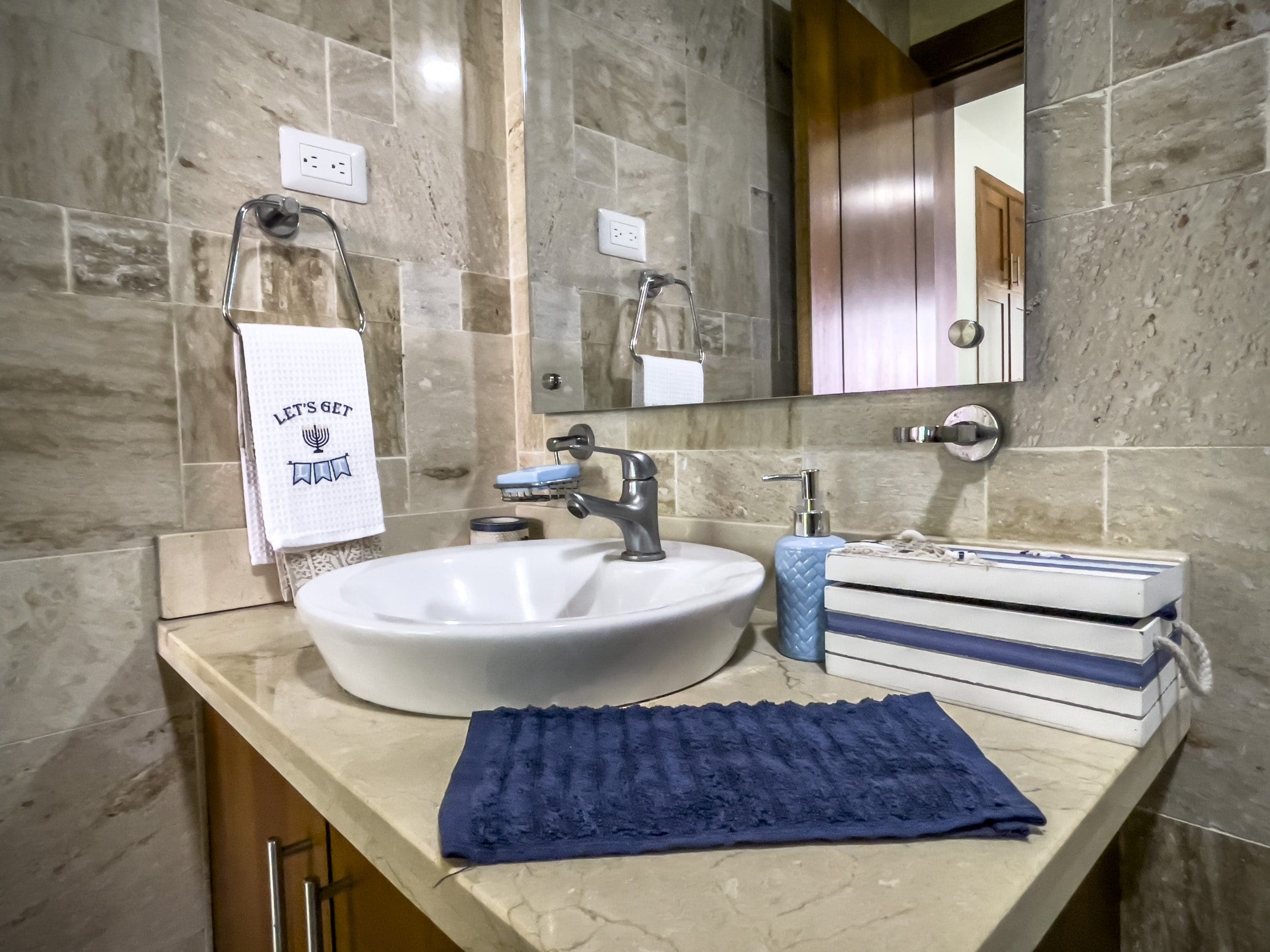 buyDRproperty Bathroom vanity with sink, mirror, and decorative items. Towel says "Let's Get. Sosua Real Estate