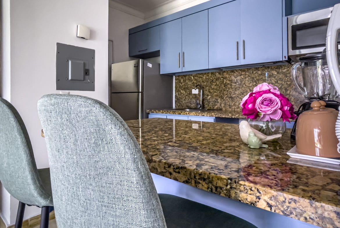 buyDRproperty Modern kitchen with blue cabinets and granite countertop in a 3 Bedroom Oceanfront Condo. Sosua Real Estate