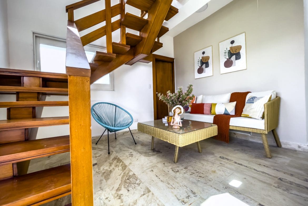 buyDRproperty Modern interior with wooden staircase, blue chair, and sofa. Sosua Real Estate