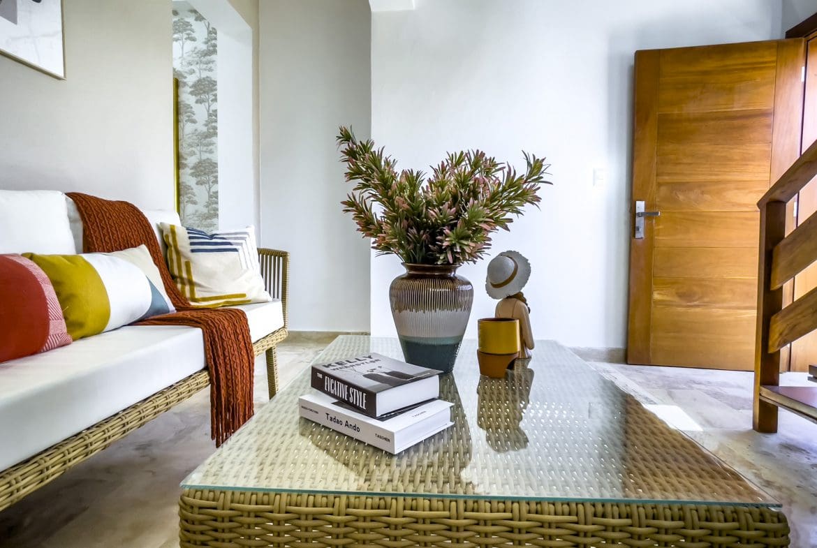 buyDRproperty Living room of an oceanfront condo for sale, featuring a woven coffee table and white couch. Sosua Real Estate