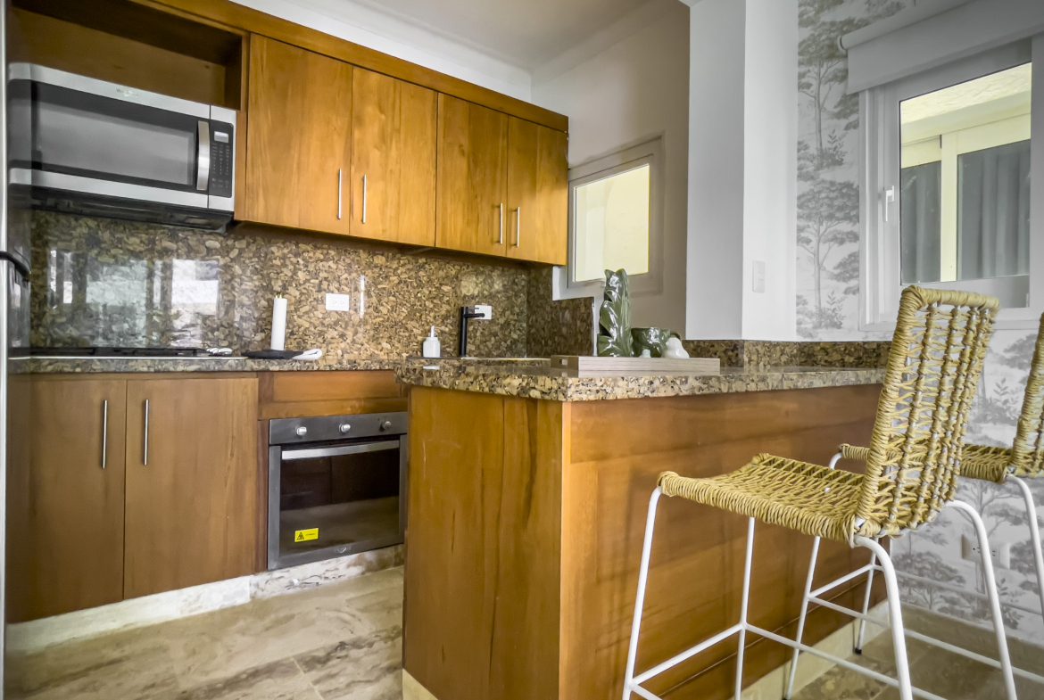 buyDRproperty Kitchen with wooden cabinets and a breakfast bar in an oceanfront condo for sale. Sosua Real Estate