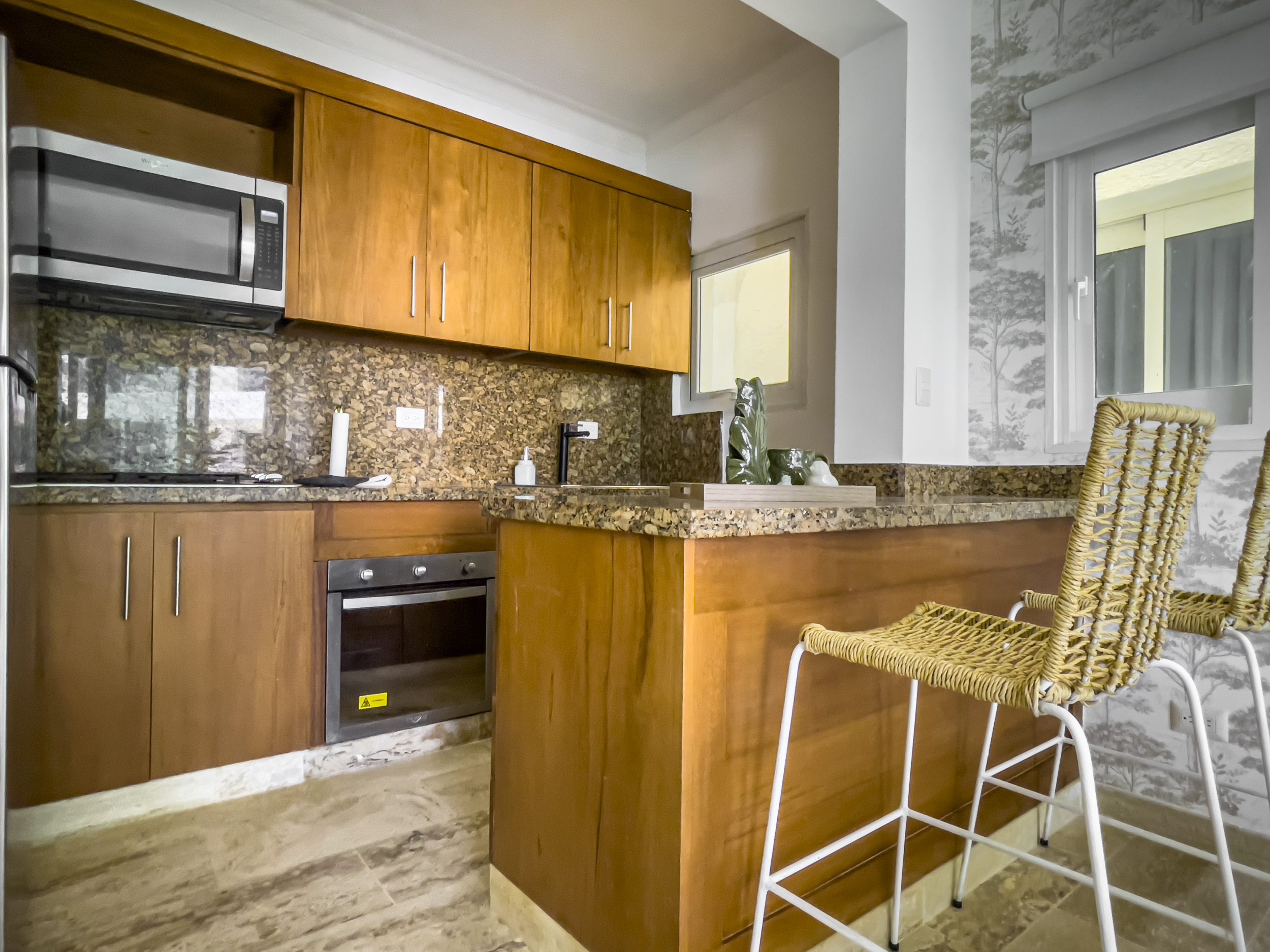 buyDRproperty Kitchen with wooden cabinets and a breakfast bar in an oceanfront condo for sale. Sosua Real Estate
