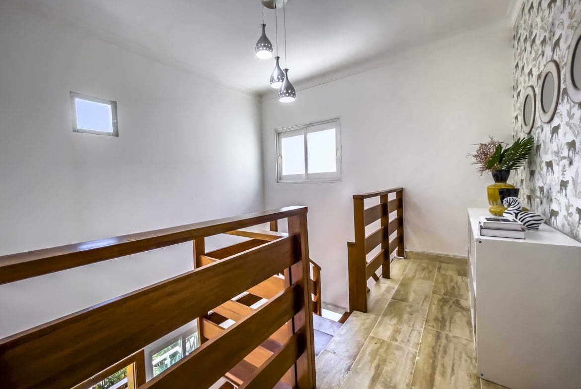 buyDRproperty Wooden staircase and hallway with decorative lighting and white walls. Sosua Real Estate