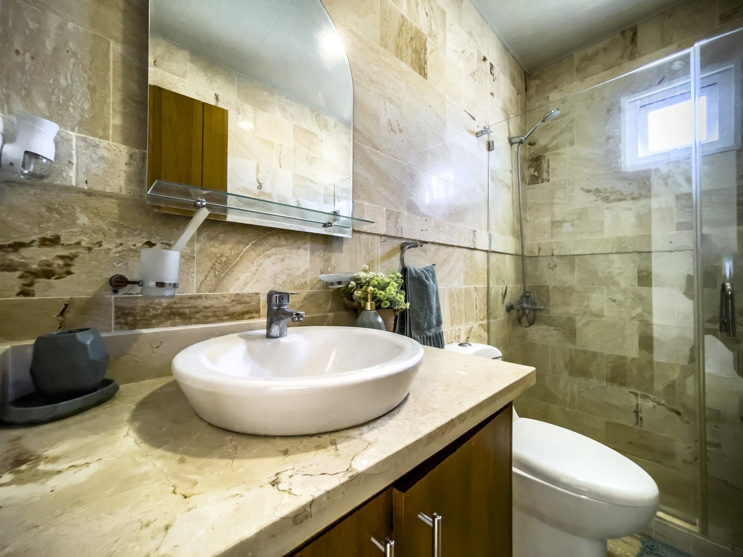 buyDRproperty Bathroom in oceanfront condo for sale in Sosua with sink, mirror, and shower. Sosua Real Estate