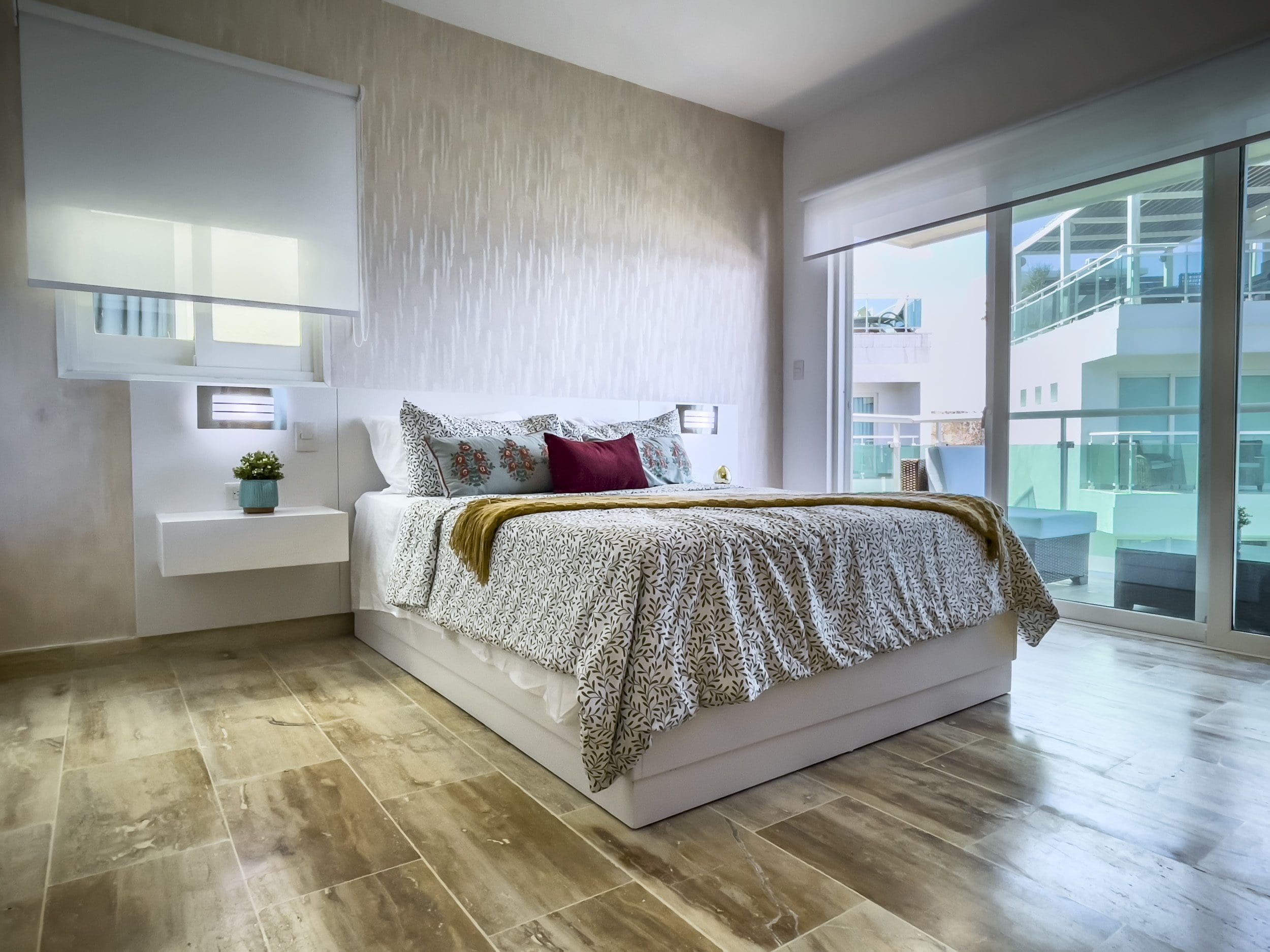 buyDRproperty Bedroom in an oceanfront condo for sale with patterned bedding, large window, and balcony view. Sosua Real Estate