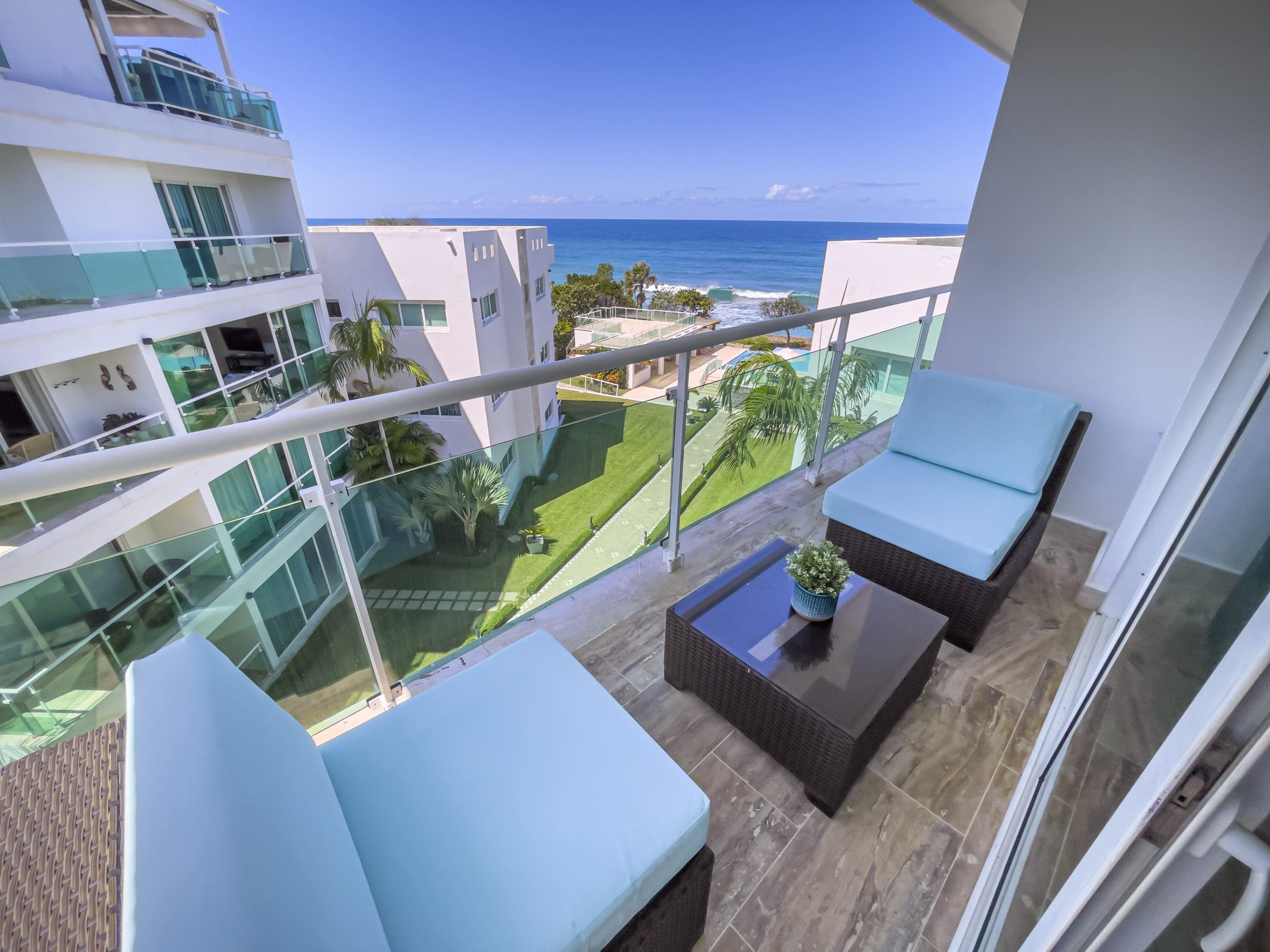 buyDRproperty Oceanfront condo balcony with blue chairs and ocean view Sosua Real Estate