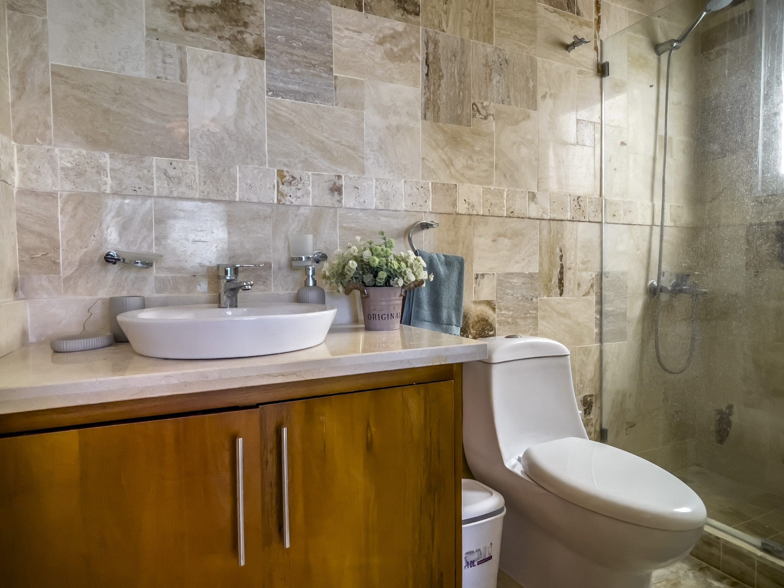 buyDRproperty Bathroom in an oceanfront condo for sale. Features a sink, toilet, and a tiled shower. Sosua Real Estate