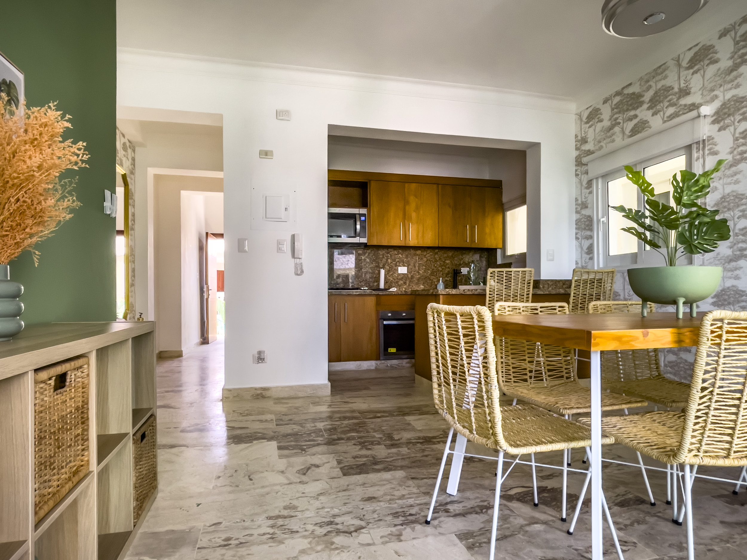 buyDRproperty Oceanfront condo for sale: dining area with table and chairs, kitchen with wooden cabinets. Sosua Real Estate