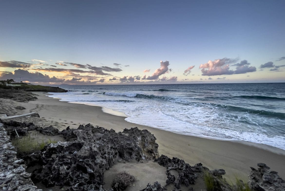 buyDRproperty Ocean view from a 3 Bedroom Oceanfront Condo with beach, waves, and rocks at sunset. Sosua Real Estate