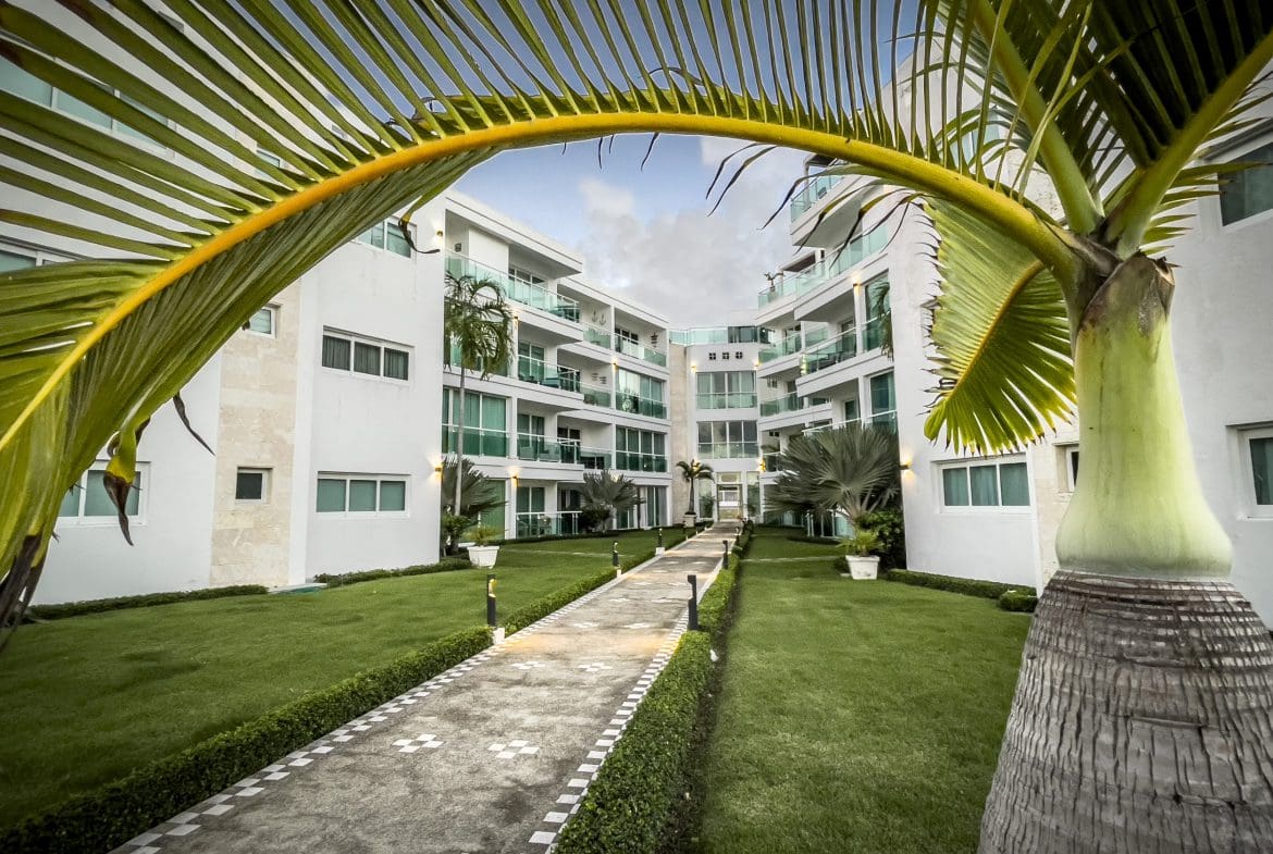 buyDRproperty Oceanfront condo complex with palm trees and pathway. Sosua Real Estate