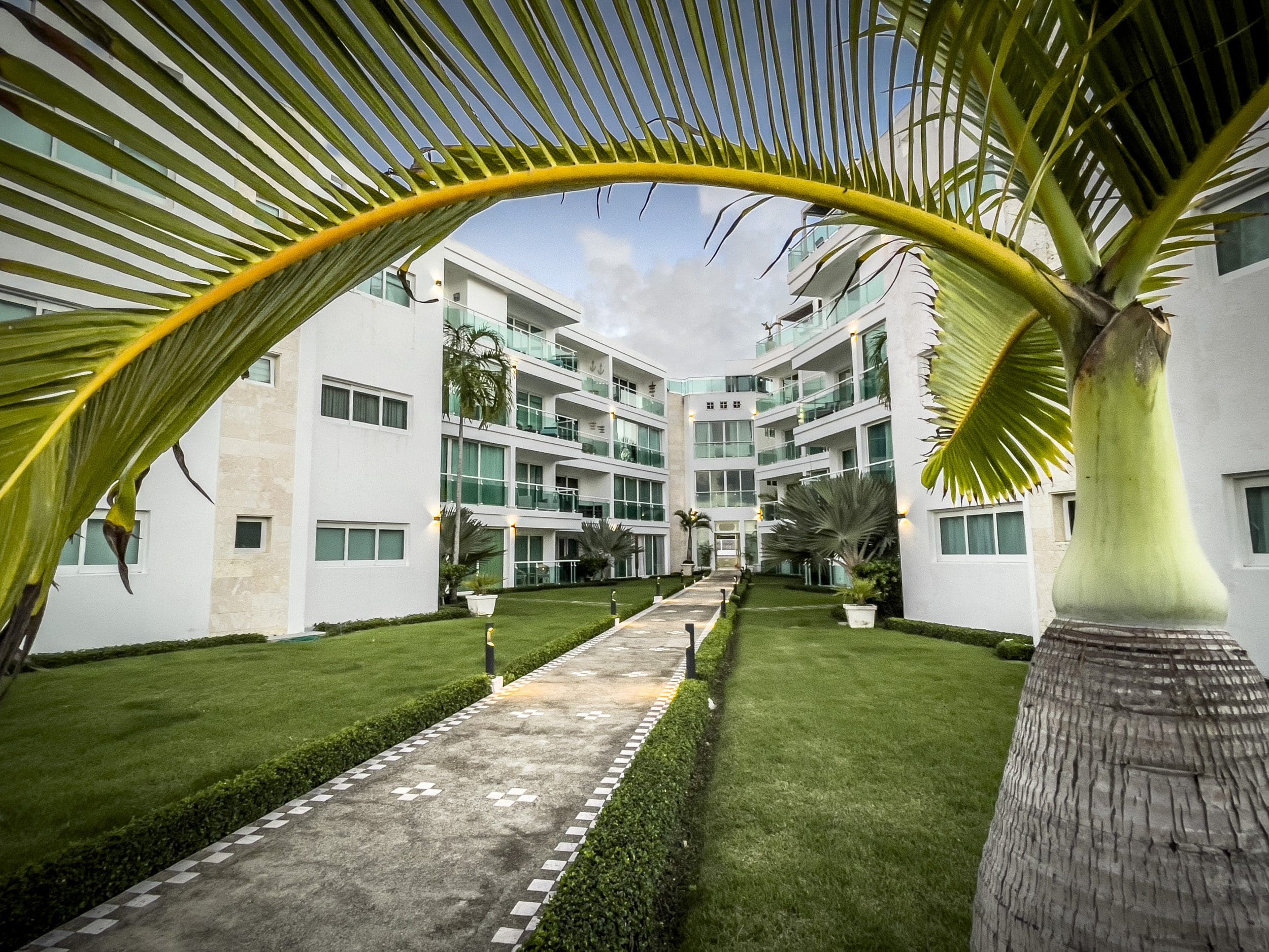 buyDRproperty Oceanfront condo complex with palm trees and pathway. Sosua Real Estate