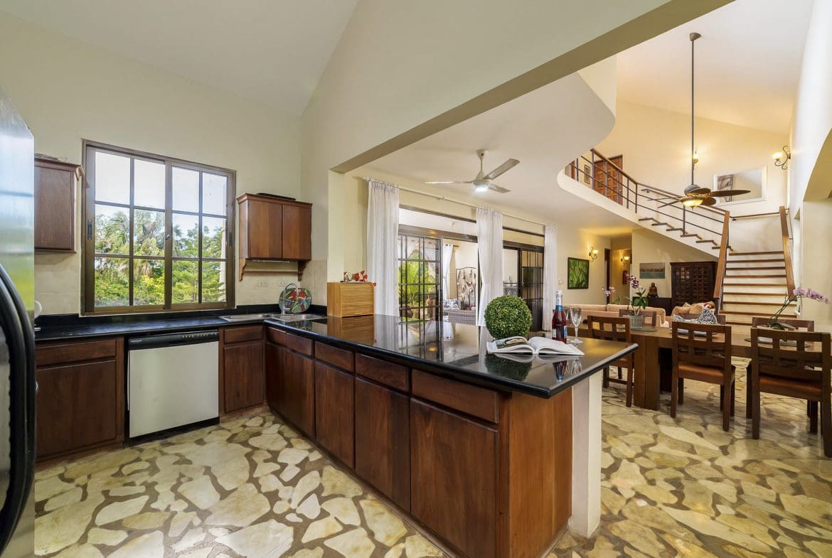 buyDRproperty Kitchen and dining area in a Beautiful 4 Bedroom Villa with dark wood cabinets and a staircase. Sosua Real Estate