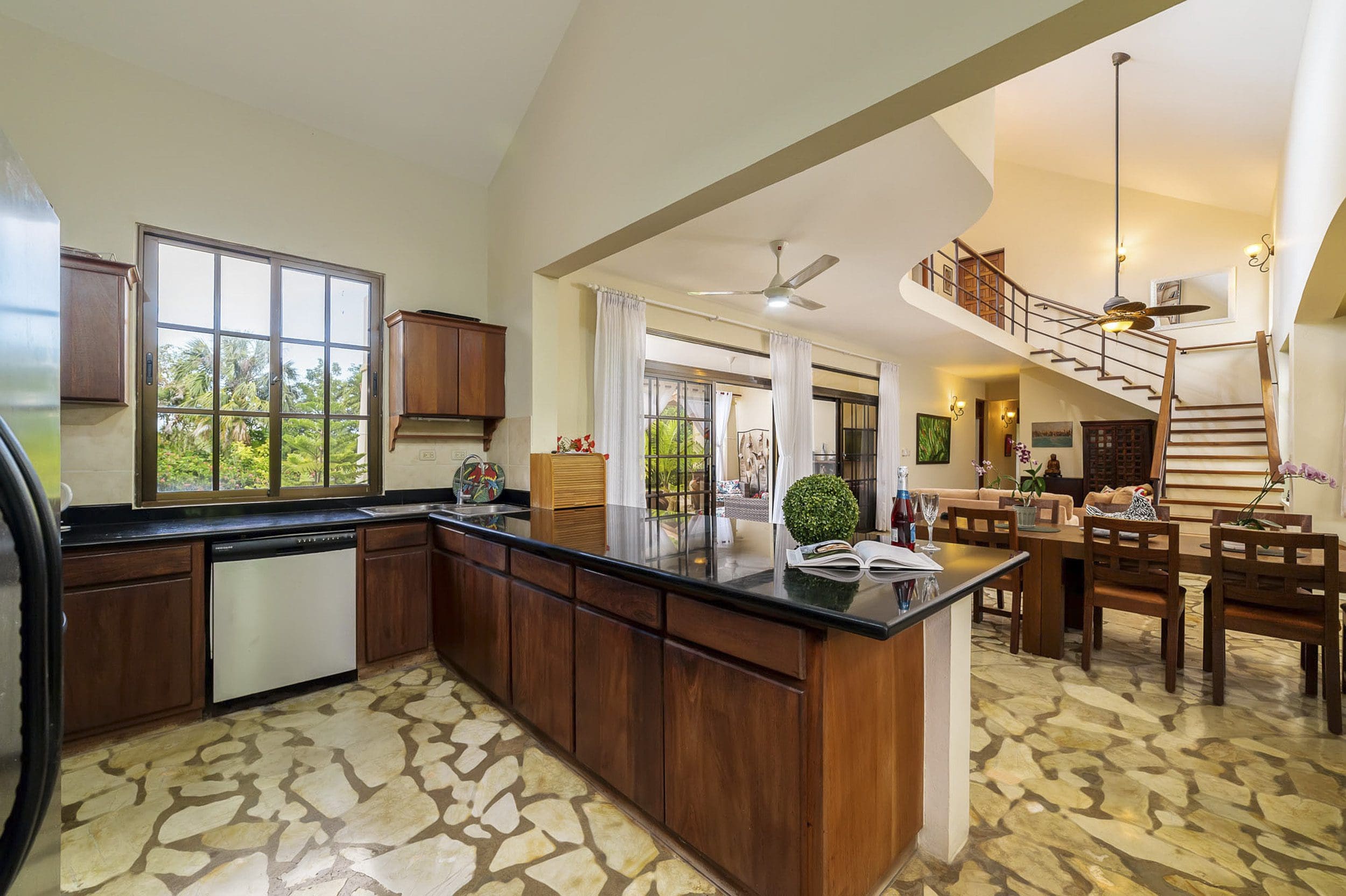 buyDRproperty Kitchen and dining area in a Beautiful 4 Bedroom Villa with dark wood cabinets and a staircase. Sosua Real Estate