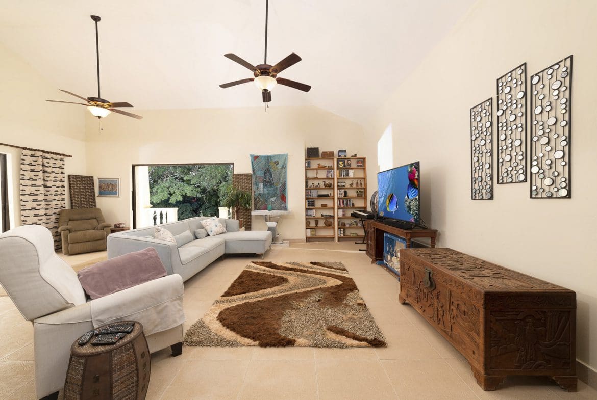 buyDRproperty Living room of a beautiful 4 bedroom villa in Sosua with light blue sectional sofa and carved wooden chest. Sosua Real Estate