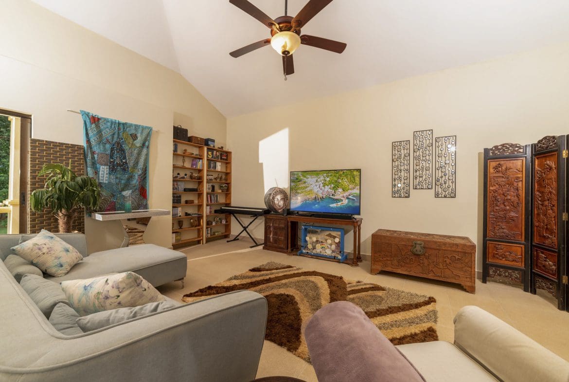 buyDRproperty Living room in a beautiful 4 bedroom villa for sale in Sosua. Features include a comfortable sofa, rug, and decorative elements. Sosua Real Estate
