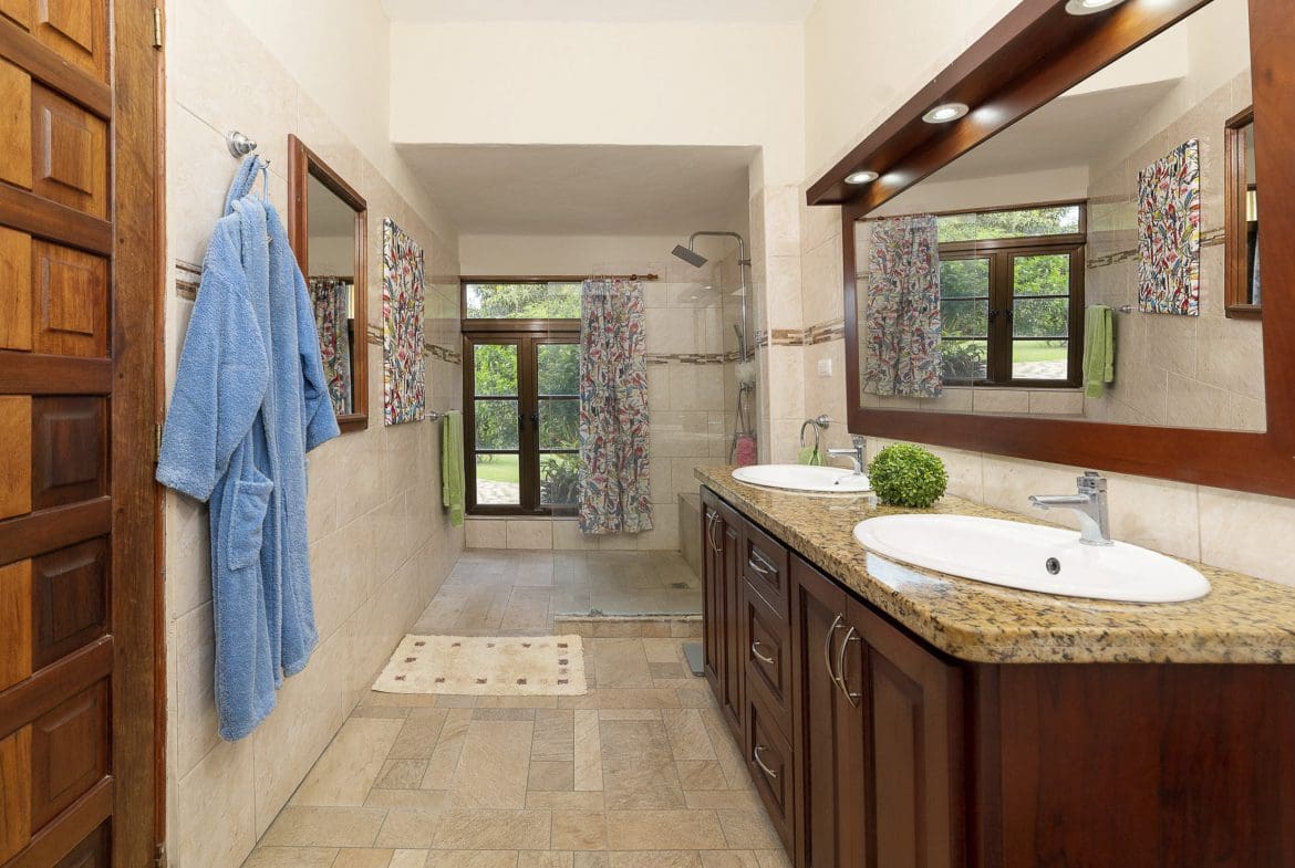 buyDRproperty Bathroom in a beautiful 4 bedroom villa for sale in Sosua, with a blue bathrobe hanging on the wall. Sosua Real Estate