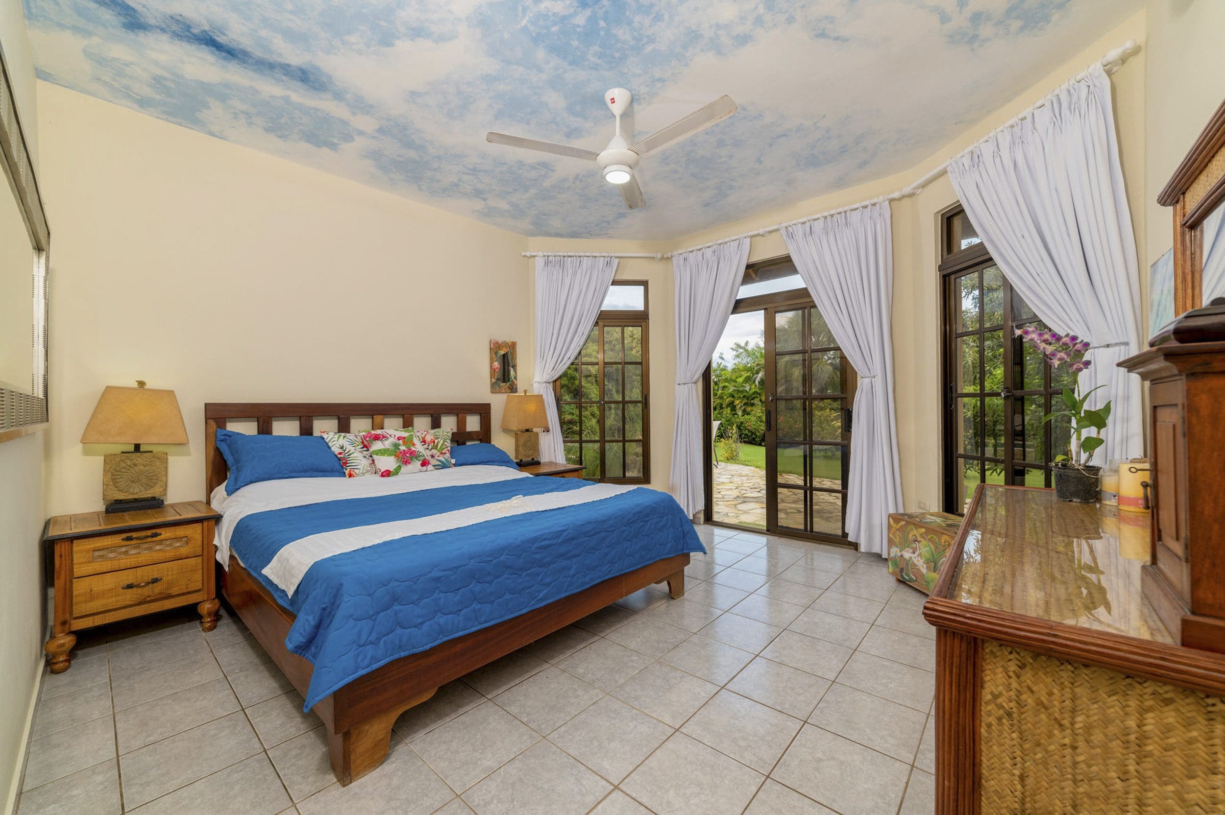 buyDRproperty Bedroom in a beautiful 4 bedroom villa for sale in Sosua, with a blue and white bedspread and a painted sky ceiling. Sosua Real Estate