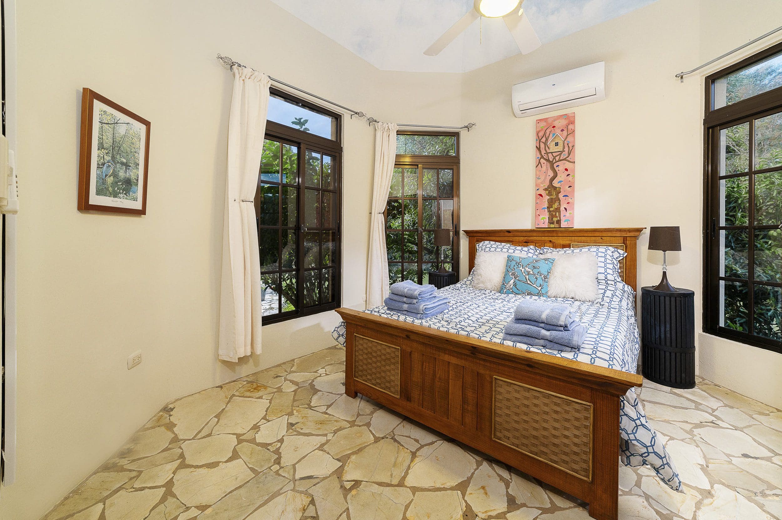 buyDRproperty Bedroom in beautiful 4-bedroom villa in Sosua, Haciendas el Choco, featuring wooden bed and stone floor. Sosua Real Estate
