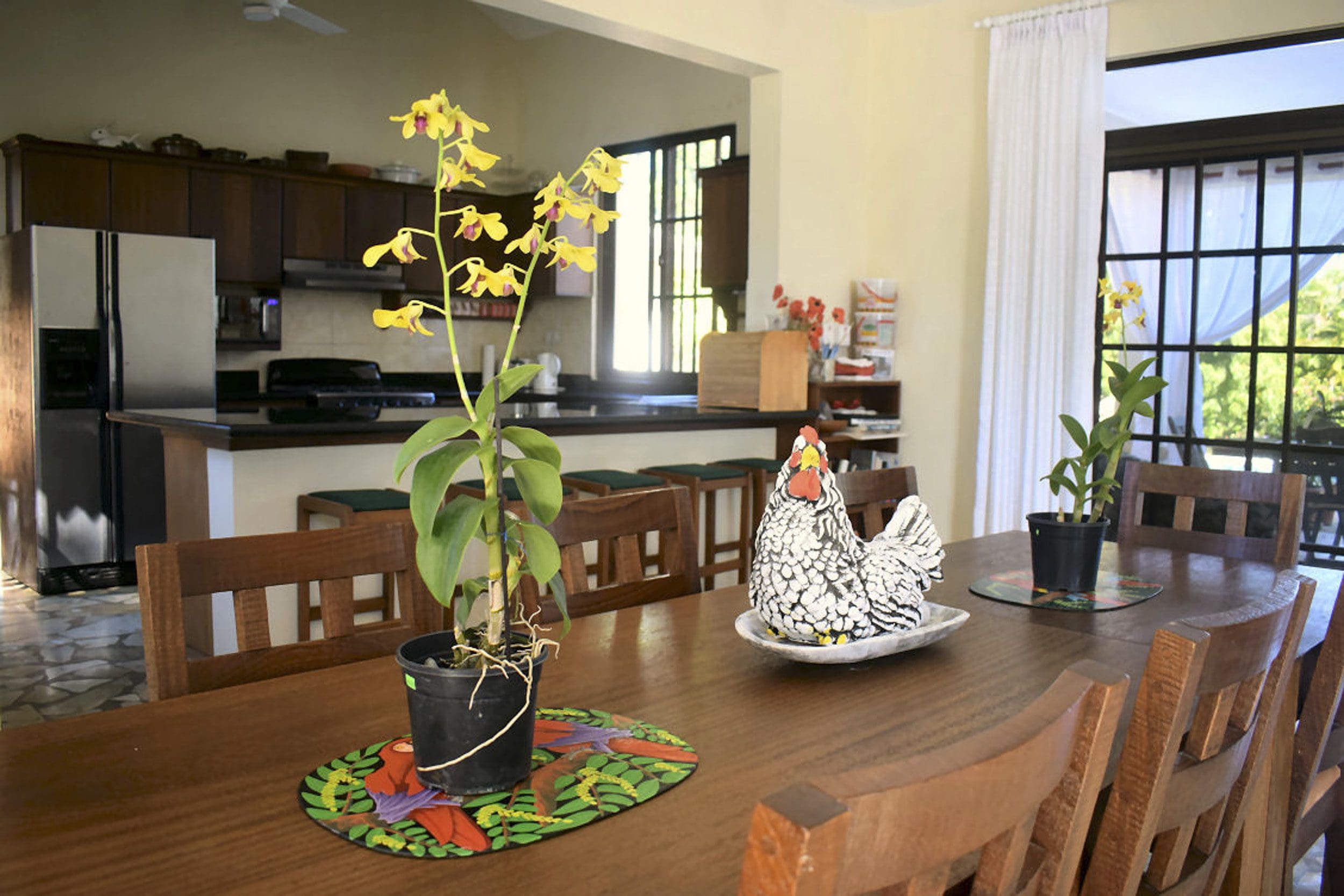 buyDRproperty Dining room interior of a Beautiful 4 Bedroom Villa in Sosua with orchid plants and a ceramic chicken. Sosua Real Estate