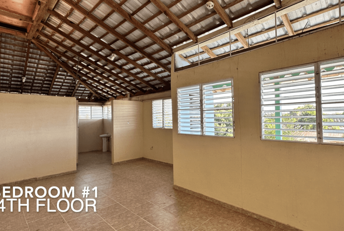 buyDRproperty Bedroom interior with high ceiling and windows, part of an affordable hotel facility. Sosua Real Estate
