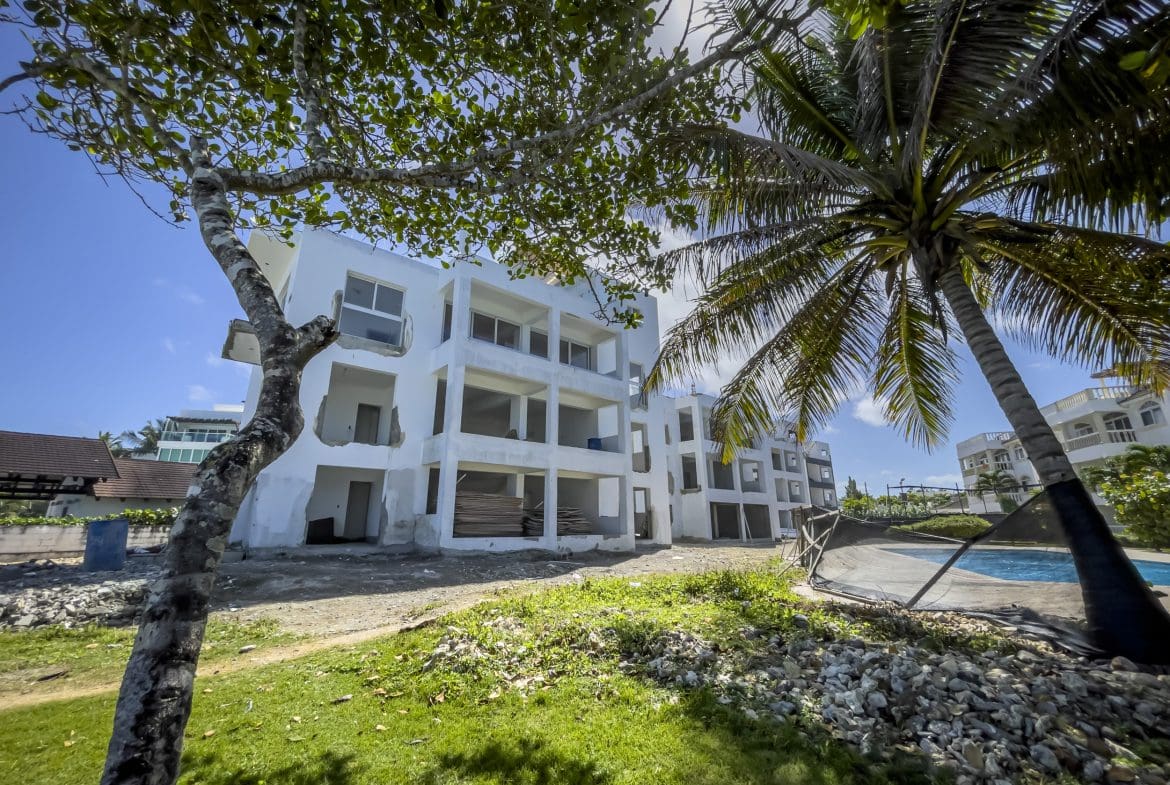 buyDRproperty Unfinished oceanfront condo in Sosua, with palm tree and blue sky. Sosua Real Estate