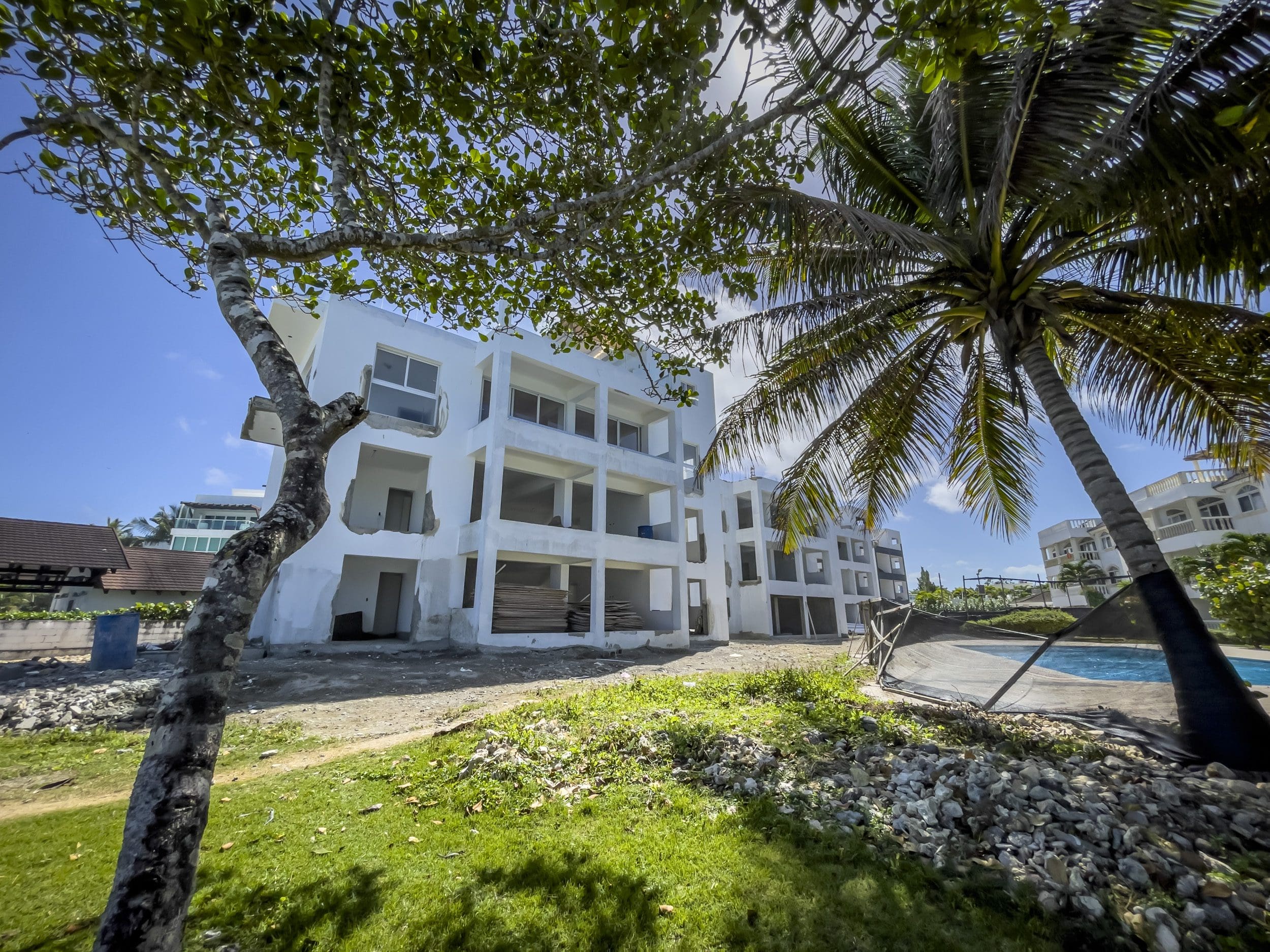 buyDRproperty Unfinished oceanfront condo in Sosua, with palm tree and blue sky. Sosua Real Estate