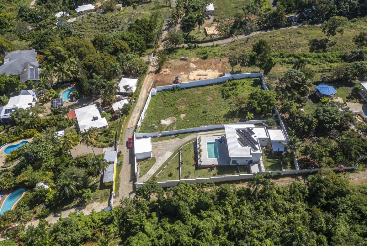 buyDRproperty Aerial view of lots for sale in La Mulata. Houses with pools and solar panels are visible. Sosua Real Estate