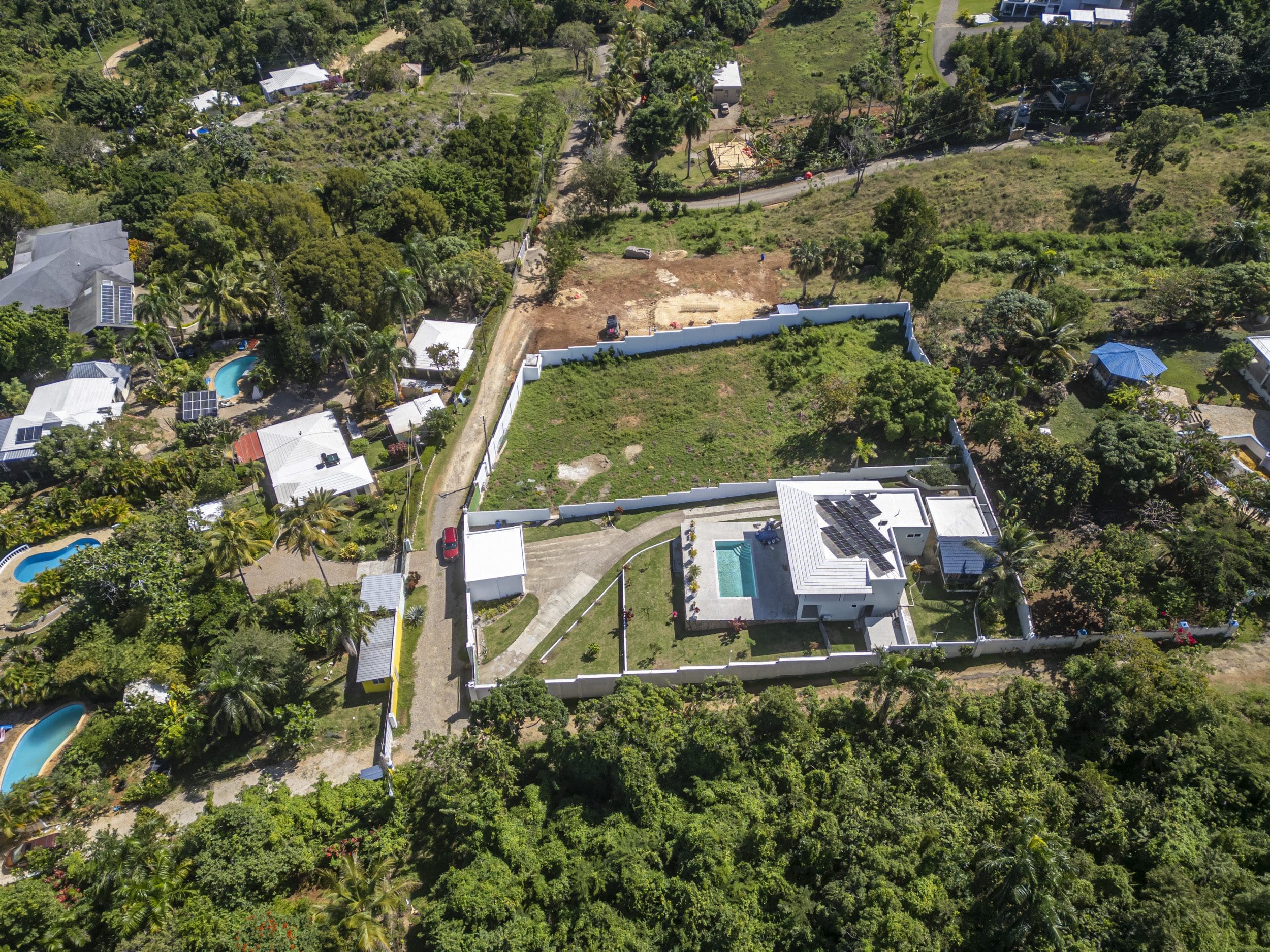 buyDRproperty Aerial view of lots for sale in La Mulata. Houses with pools and solar panels are visible. Sosua Real Estate