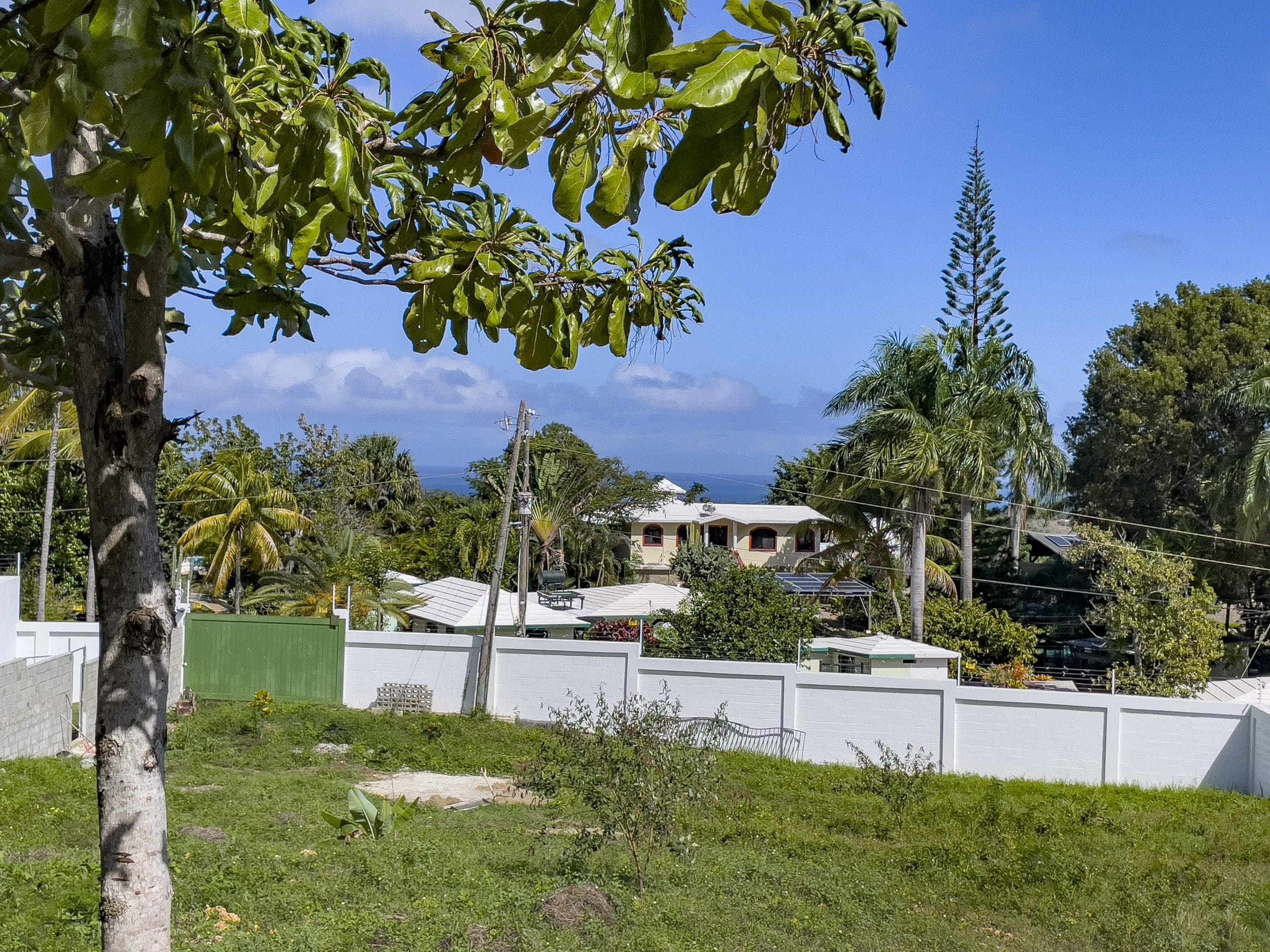 buyDRproperty Lots for sale in La Mulata with ocean views, featuring a property with a white wall and lush greenery. Sosua Real Estate