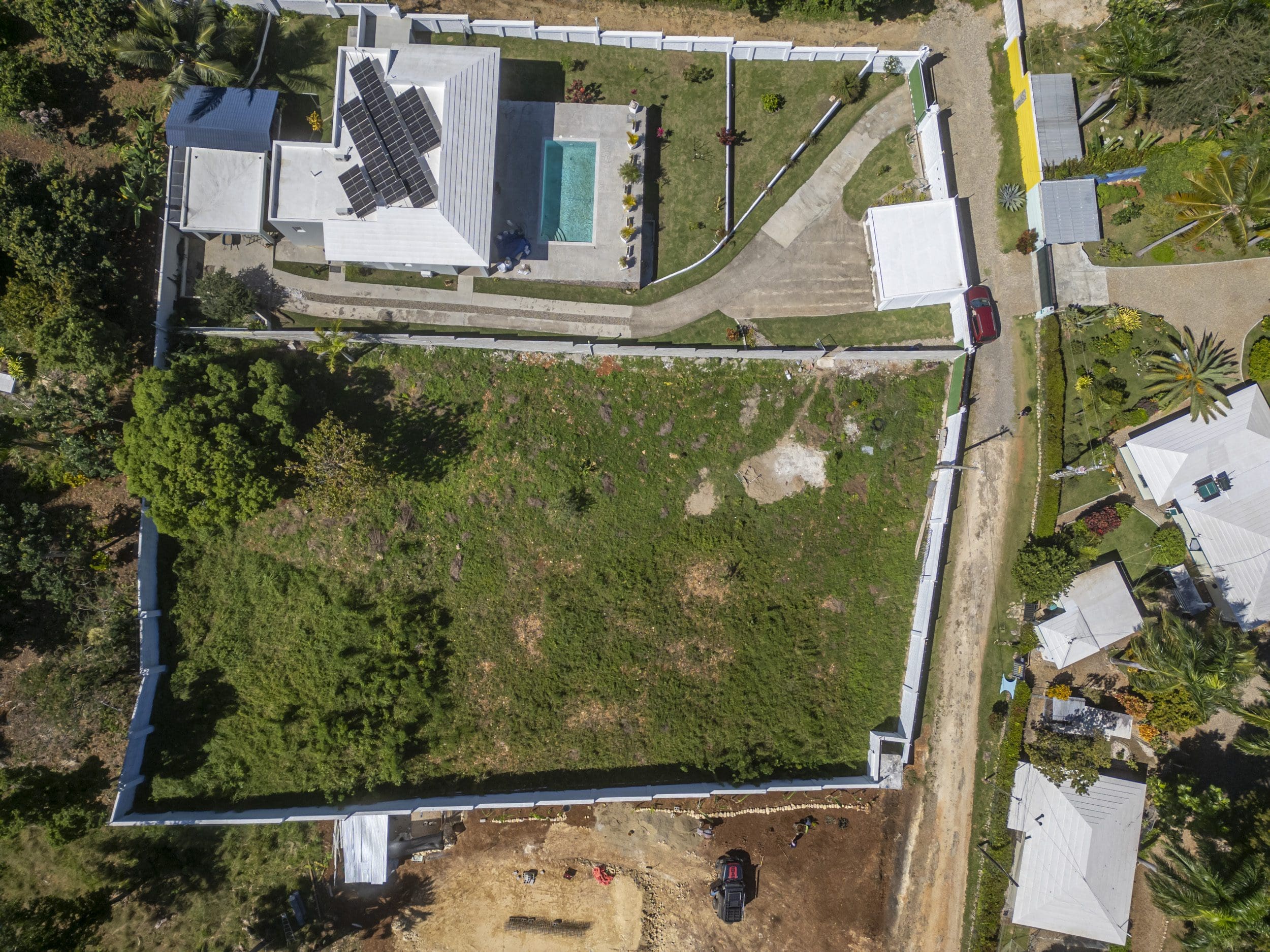 buyDRproperty Aerial view of lots for sale in La Mulata, showing a house with a pool and a large empty lot. Sosua Real Estate