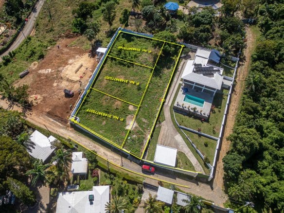 buyDRproperty Aerial view of lots for sale in La Mulata, featuring marked land parcels and a house with a pool. Sosua Real Estate