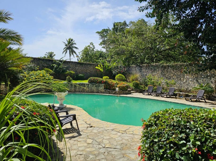 buyDRproperty Hotel near the beach: Pool with lush landscaping and stone wall. Sosua Real Estate