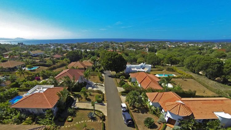 buyDRproperty Aerial view of 4 Bedroom Villa TAINO with red tile roof and lush landscaping near the ocean. Sosua Real Estate