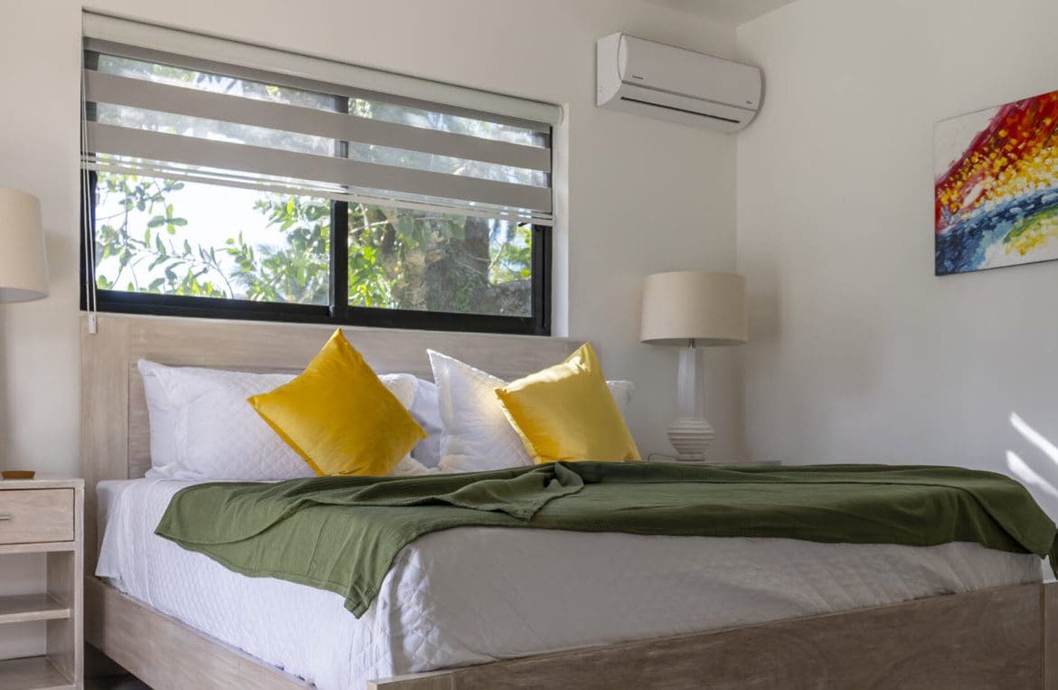 buyDRproperty Bedroom in a Beautiful Villa SUNSEEKER in Casa Linda with yellow pillows and green blanket. Sosua Real Estate