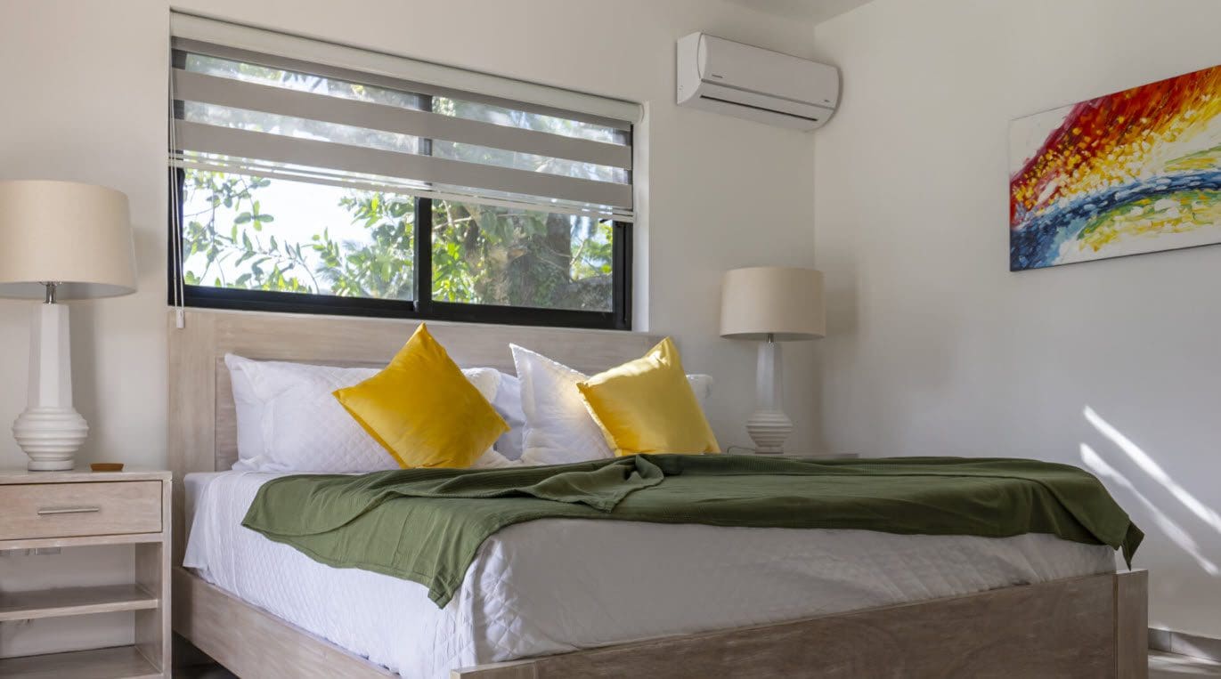 buyDRproperty Bedroom in a Beautiful Villa SUNSEEKER in Casa Linda with yellow pillows and green blanket. Sosua Real Estate