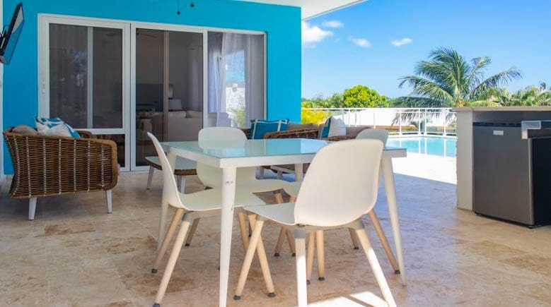 buyDRproperty Outdoor patio with a Beautiful Villa SUNBREEZE, white table and chairs, with a pool view. Sosua Real Estate