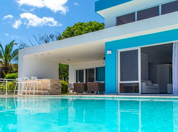 buyDRproperty Beautiful Villa SUNBREEZE with a pool, blue accents, and a sunny sky. Sosua Real Estate