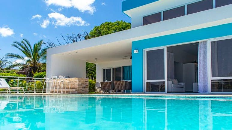 buyDRproperty Beautiful Villa SUNBREEZE with a pool, blue accents, and a sunny sky. Sosua Real Estate