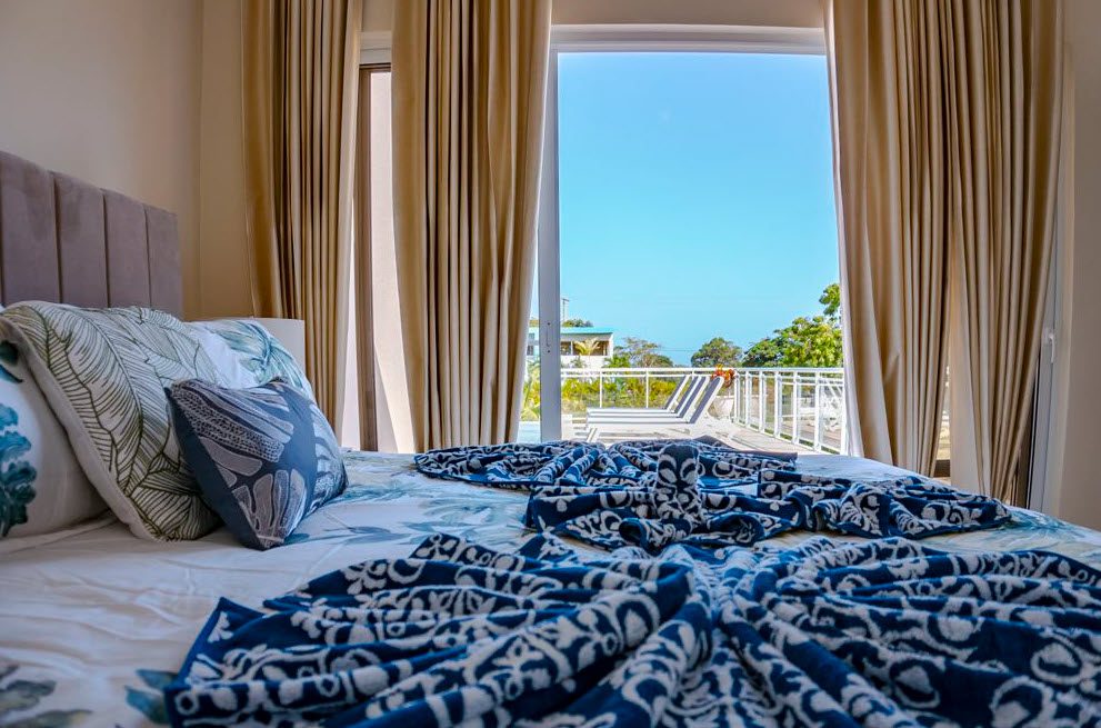 buyDRproperty Bedroom with beautiful villa views in Casa Linda. Blue patterned blanket on the bed. Sosua Real Estate